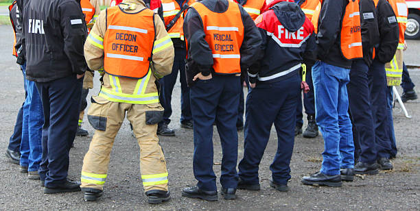 Disaster Team Discussion Circle In any urban area the fire departments and emergency response teams will conduct disaster preparedness drills. This group of team members gathers around to discuss options. biochemical weapon photos stock pictures, royalty-free photos & images