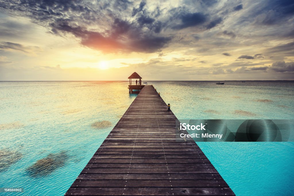 Fakarava Sunset at Jetty French Polynesia Beautiful Polynesian sunset over the clear waters of the South Pacific. Silhouettes of people standing on  Jetty. Fakarava, French Polynesia. Fakarava Stock Photo
