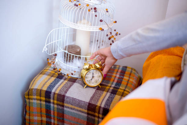 female hand reaching to turn off alarm clock.
