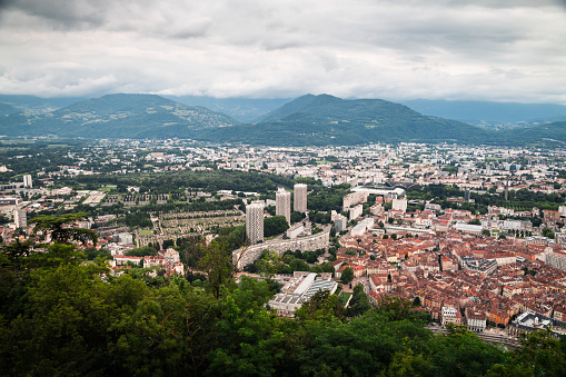 High angle view of Grenoble cityscape viewed from The Fort of the Bastille point of view. This image was taken in Grenoble city on a cloudy summer day, in the department of Isere, Auvergne-Rhône-Alpes region in France, Europe.