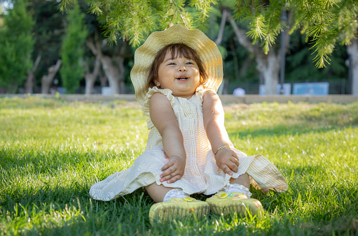 Photo of a happy baby girl wearing a hat in nature