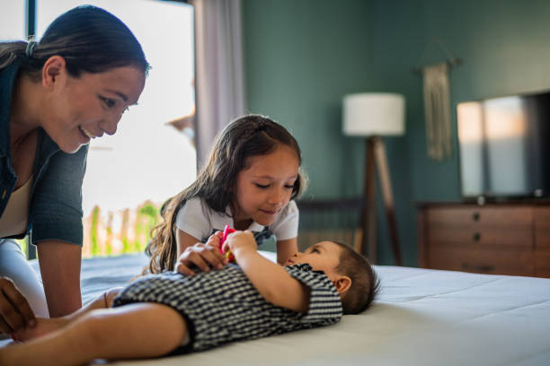 Mother and daughter playing with baby boy in the bedroom at home Mother and daughter playing with baby boy in the bedroom at home 6 9 months stock pictures, royalty-free photos & images