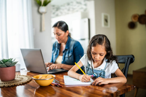 istock Girl studying while mother is using laptop in the background at home 1585588500