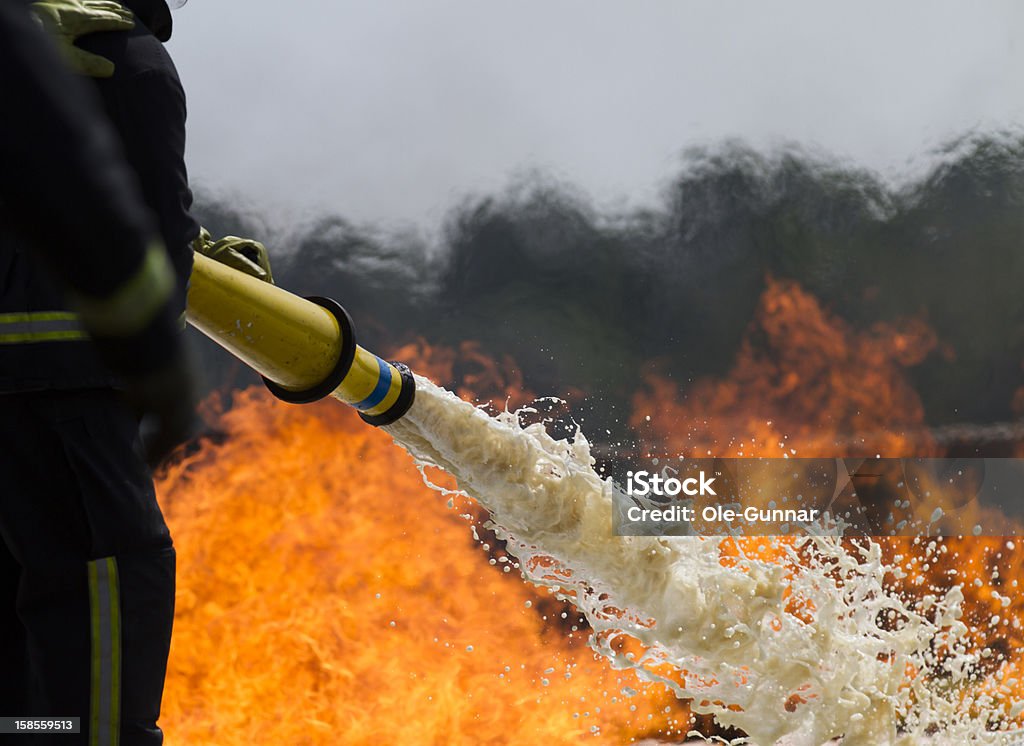 Firefighting foam. Fire-fighters applying foam to a fire. Foam - Material Stock Photo