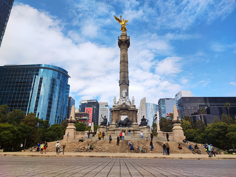 Celebrate the spirit of liberty and national pride with this powerful editorial photograph featuring The Monument to Independence, fondly known as El Ángel de la Independencia, gracing the vibrant streets of Mexico City. Majestic and iconic, this towering monument stands as a timeless symbol of Mexico's hard-fought independence.\n\nThe striking image showcases the monument's intricate architectural details, highlighted against the backdrop of a clear blue sky. Its resplendent golden figure, the Angel of Independence, raises the victory column to the heavens, commemorating the heroes who fought for the country's autonomy.