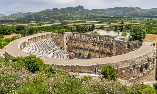 A Roman theater, at Aspendos surrounded with green agricultural fields and mountain range in the spring, Antalya, Turkey