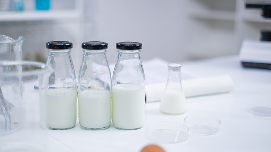 Bottle of a sample milk. Concept of nutrition, lactose, protein, bacteria, fat and glucose laboratory. Dairy milk test. Nutritionist is checking and analyze the quality of factory milk product