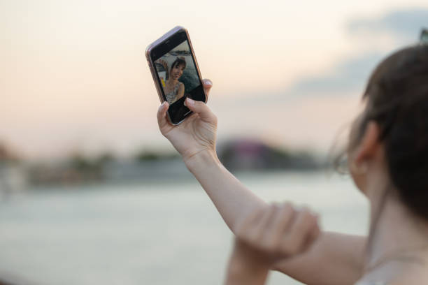 istock Young lady is taking a selfie at sunset. 1585663309