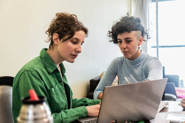 istock Female friends using laptop while studying at home 1585676735