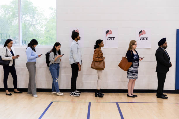 un groupe diversifié d’électeurs fait la queue pour recevoir leur bulletin de vote - election presidential candidate usa bipartisan photos et images de collection