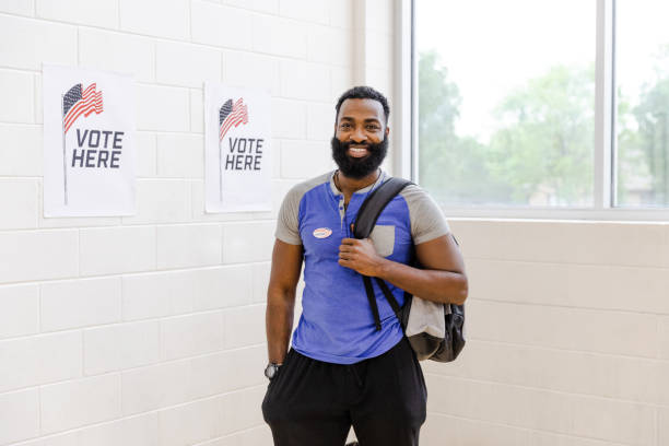 un étudiant de sexe masculin moyen sourit à la caméra après avoir voté au centre communautaire - election presidential candidate usa bipartisan photos et images de collection