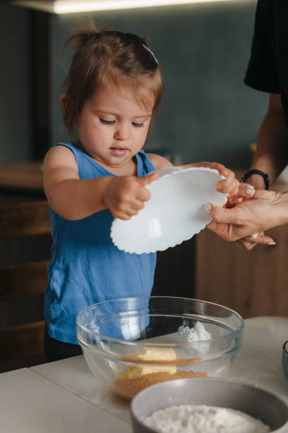 mother with little daughter cooking dessert bakery in the kitchen, enjoying preparing the dough. domestic lifestyle. happy lifestyle. fun family. food preparation. - chef cookie dishware domestic kitchen imagens e fotografias de stock