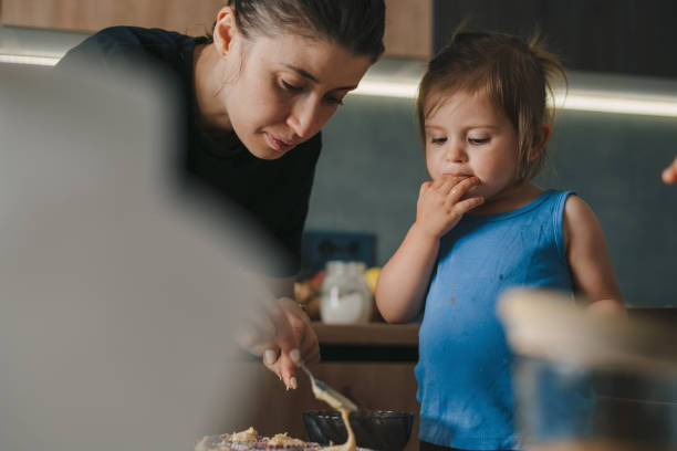 happy mother with her kid pouring cake batter in cup cake moulds. happy family. food preparation. fun family. - chef cookie dishware domestic kitchen imagens e fotografias de stock