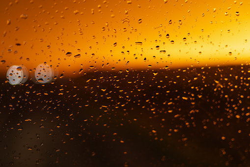 Rain drops on a window pane of a car. sunset unfocused