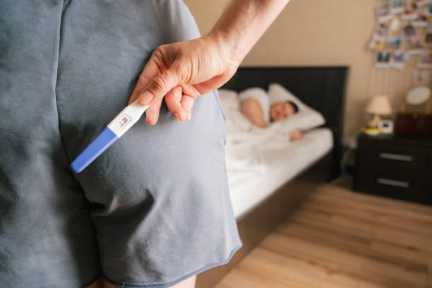 istock woman holding positive pregnancy test surprise for husband 1585789310