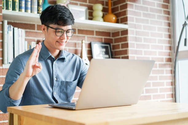 istock close up asian man make gesture hand about hello sign language to teaching or learning from webinar in home for lifestyle concept 1585794781