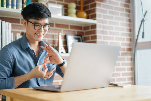 close up asian man make gesture hand of deaf sign language to teaching or learning from webinar in home for lifestyle concept