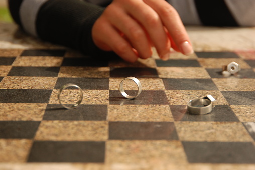 Silver wedding rings and woman's hand on the chess board. Concept of love, marriage, together, game, lovers.