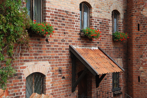 Facade of cozy brick house with windows, doorway and flowers.