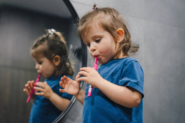 istock Adorable child learning how to brush her teeth in the bathroom. Brushing teeth 1585835712