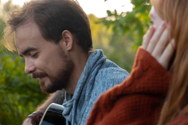 istock Young bearded man playing guitar and sitting near his girlfriend 1585837361