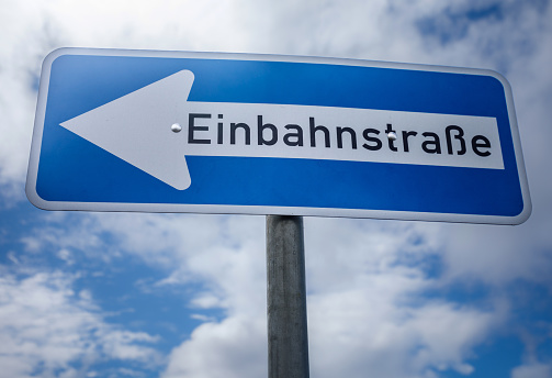 A one-way street sign against a blue sky in Germany