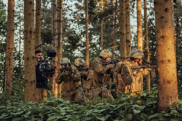 Videographer with Professional Movie Video Camera Gimbal Stabilizing Equipment Taking Action Shoot of Soldiers in Action in Forest