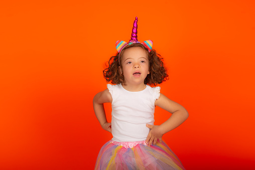 eautiful girl playing during photo shoot in studio. Isolated on orange color background.