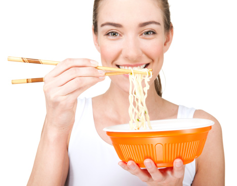 Beautiful smiling young woman eats noodles. Adobe RGB