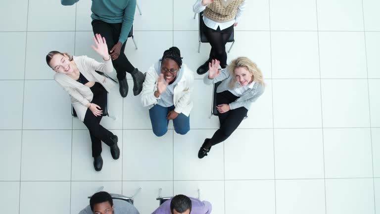 group of young business people cheerfully wave their hands looking at the camera .