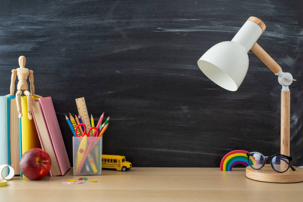istock Get inspired by this school-oriented setup: side view photo of desk essentials, stationery, books, lamp, mannequin, glasses, apple and more against chalkboard backdrop, offering space for text or ads 1585980080