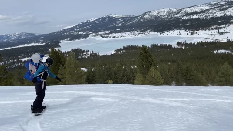 Dad snowboards with baby in the mountains of Lake Tahoe