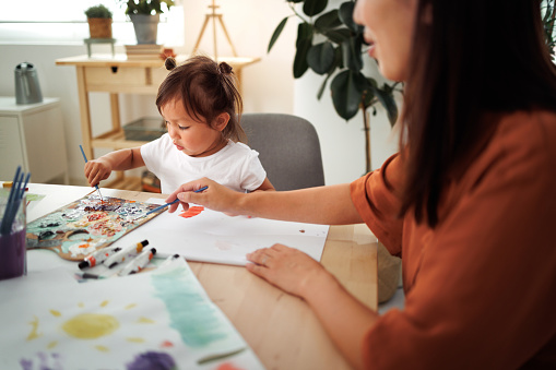 Cute little girl painting with her mother at home