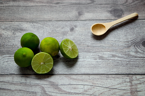 limones verdes y cuchara de madera sobre una mesa rústica photo