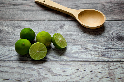 limones verdes y cuchara de madera sobre una mesa rústica photo