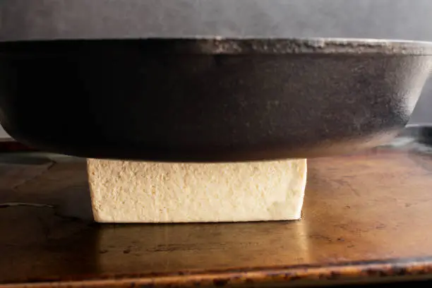 Pressing the water out of a block of bean curd using a heavy pan