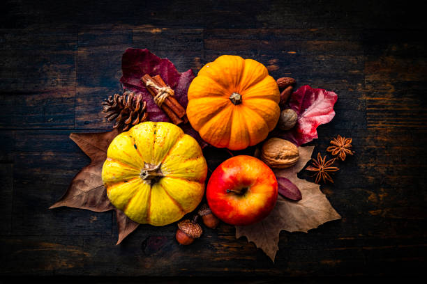 Autumn decorative mini pumpkins with apple and fall leaves on dark wood background. Thanksgiving or Halloween holiday stock photo