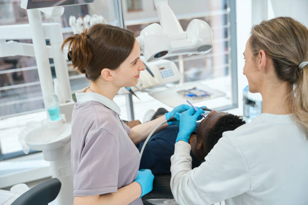 istock Nurse holding saliva ejector while professional dentist doing treatment 1586071425