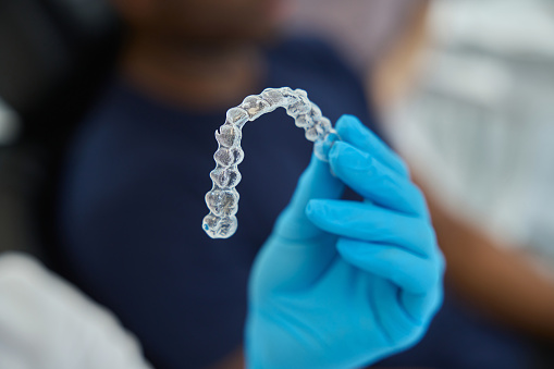 Woman dental aesthetic clinic worker holding clear aligners, that put gentle pressure on patient teeth to gradually reposition them
