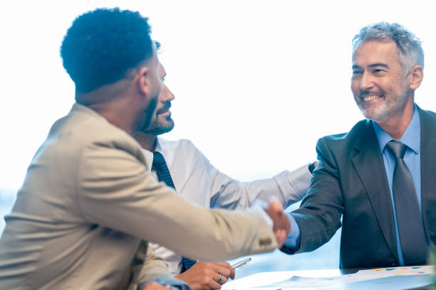istock Businessmen shaking hands at the board room table 1586111725