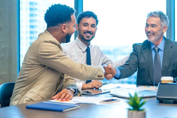 istock Businessmen shaking hands at the board room table. 1586112775