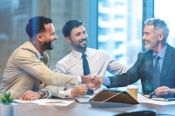 istock Businessmen shaking hands at the board room table. 1586124851