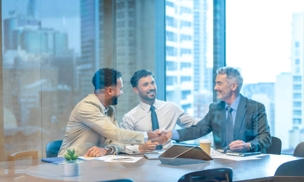 Businessmen shaking hands at the board room table.