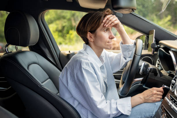 istock Stressed middle aged woman driving car having problems on road looking ahead. 1586150053