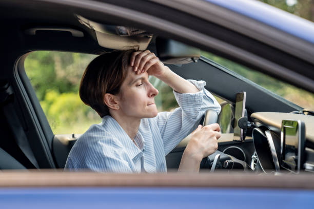 istock Stressed middle aged woman driving car having problems on road looking ahead. 1586150074
