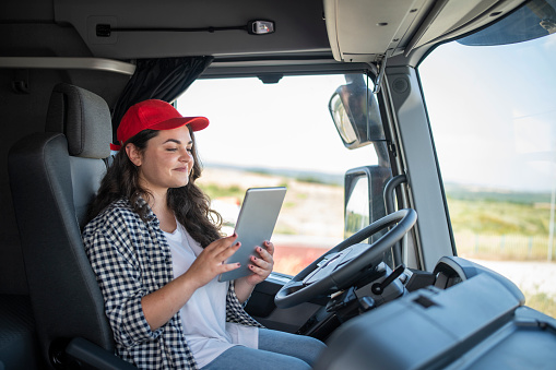 Female truck driver using technology/using phone at work.