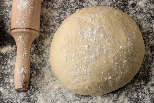 istock Dough for baking and rolling pin on a dark background. top view. 1586244520