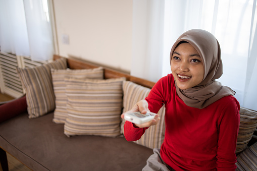 Woman turning on air conditioner with remote