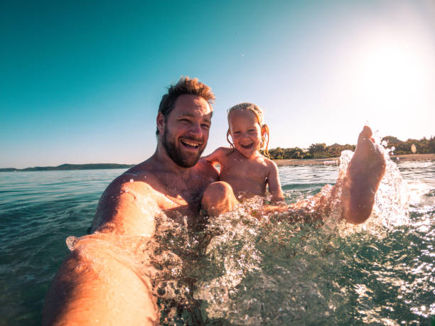 istock Joyful Father and Son Splashing Water 1586270963