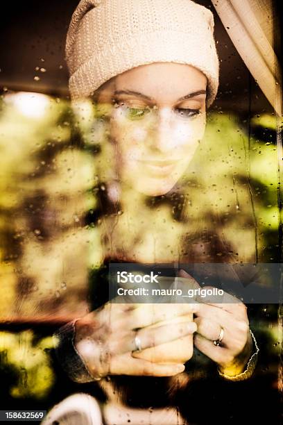 Pensativo Mujer Mirando A Través De Una Ventana Foto de stock y más banco de imágenes de Día - Día, Invierno, Oscuro